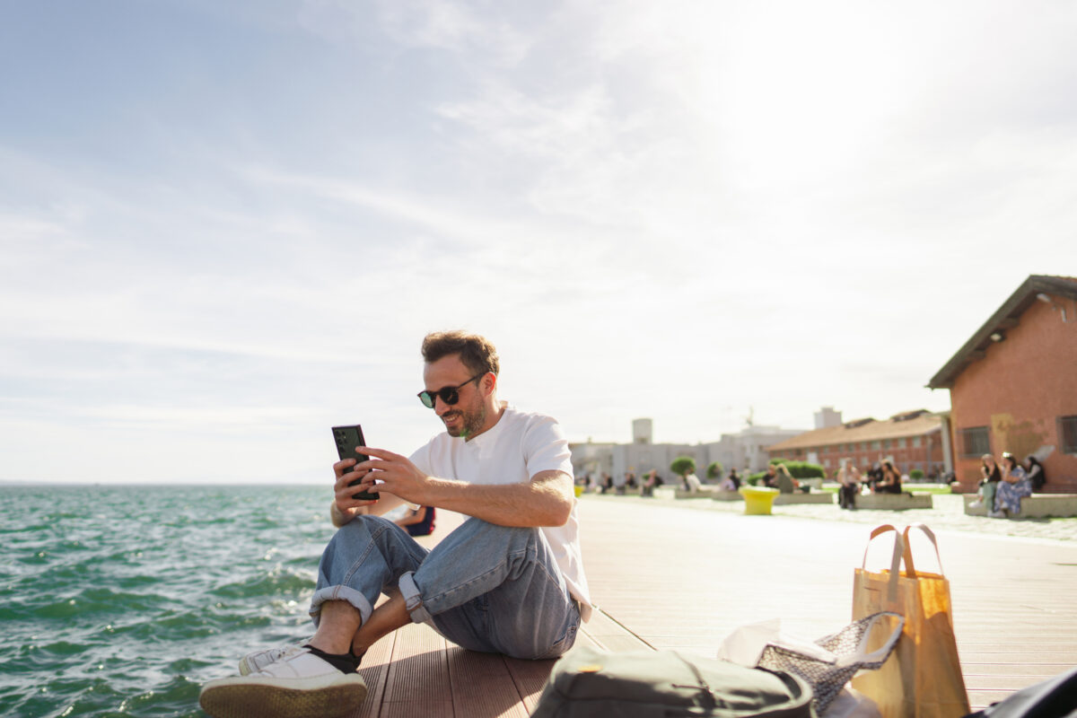 Young man taking a break during the day, sitting on a pier and enjoying springtime sun