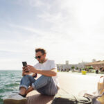 Young man taking a break during the day, sitting on a pier and enjoying springtime sun