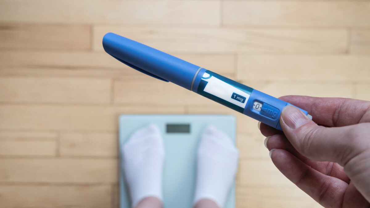 Ozempic Insulin injection pen for diabetics and weight loss. Woman weighs herself and holds Ozempic in her hand. Weight loss concept.