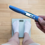 Ozempic Insulin injection pen for diabetics and weight loss. Woman weighs herself and holds Ozempic in her hand. Weight loss concept.