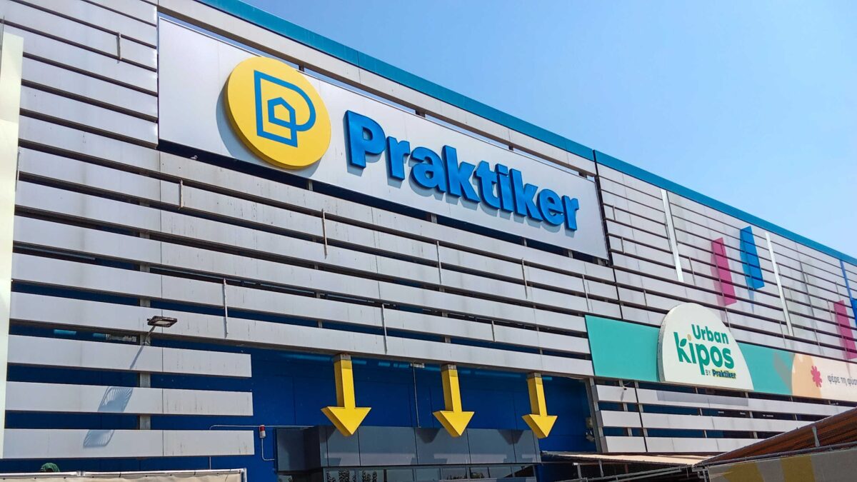 The entrance of the Praktiker department store with people entering in it.