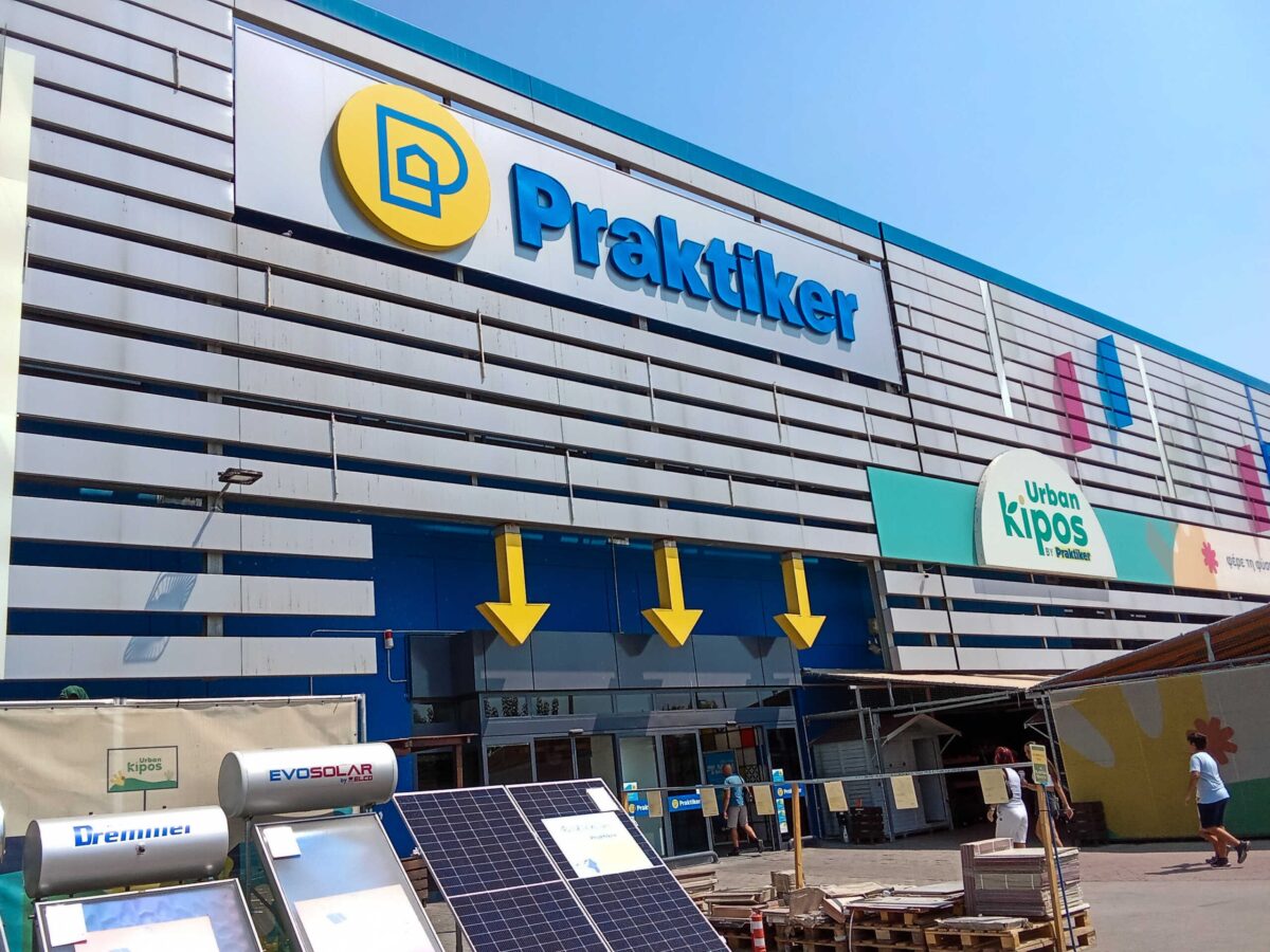 The entrance of the Praktiker department store with people entering in it.