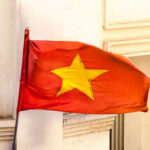 A red national flag of Vietnam stands as a significant symbol of the country, fluttering above the streets and embodying the spirit of the nation.