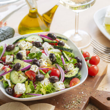 Healthy and fresh Greek salad plate bowl on dining table. Feta cheese, black olives, tomatoes and cucumber
