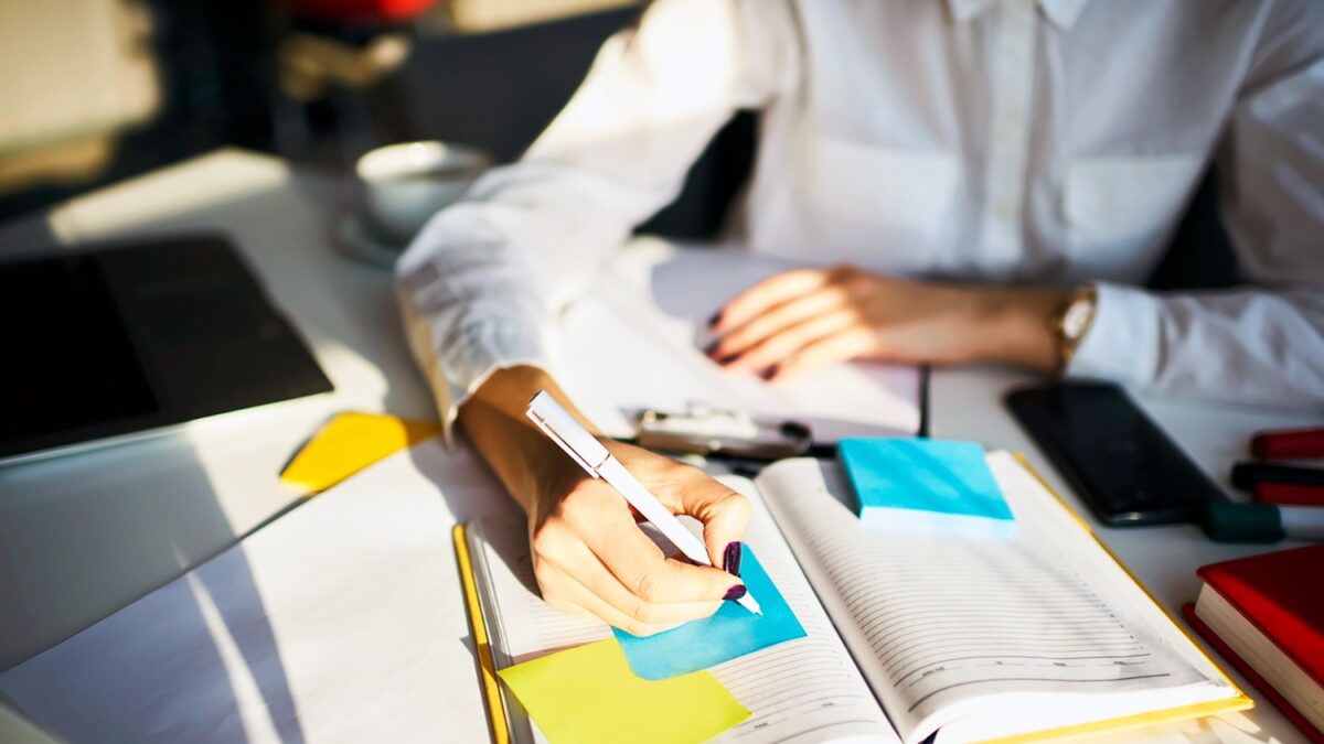 Cropped image of creative female secretary creating planning for executive noting important meeting and events organizing work of busy boss while sitting at working place in coworking office