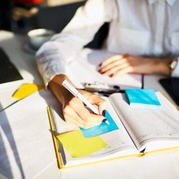 Cropped image of creative female secretary creating planning for executive noting important meeting and events organizing work of busy boss while sitting at working place in coworking office