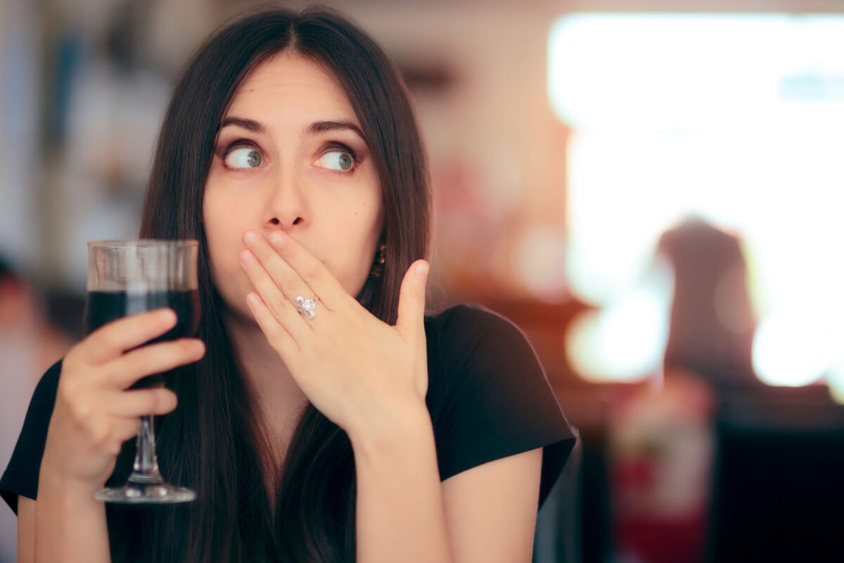 Woman covering her moth after drinking cola