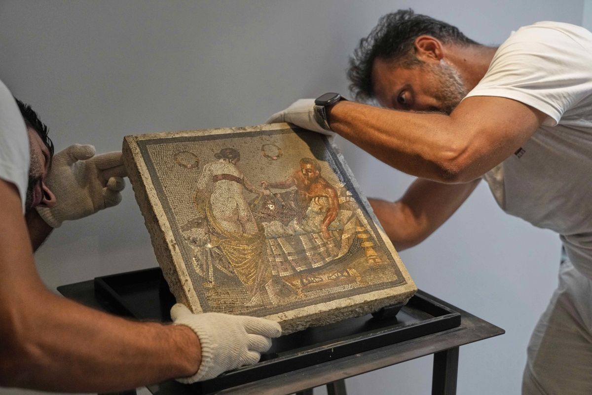 Συντηρητές εκθέτουν ένα ρωμαϊκό ψηφιδωτό που απεικονίζει ένα ζευγάρι ερωτευμένων, το οποίο επαναπατρίστηκε από τη Γερμανία, στο αρχαιολογικό πάρκο της Πομπηίας