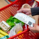 Close up of unrecognizable customer checking her receipt after purchasing groceries in the supermarket - Home shopping concepts