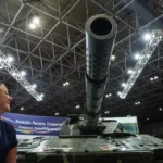 A person reacts next to a tank during LAAD, the biggest military industry expo in Latin America