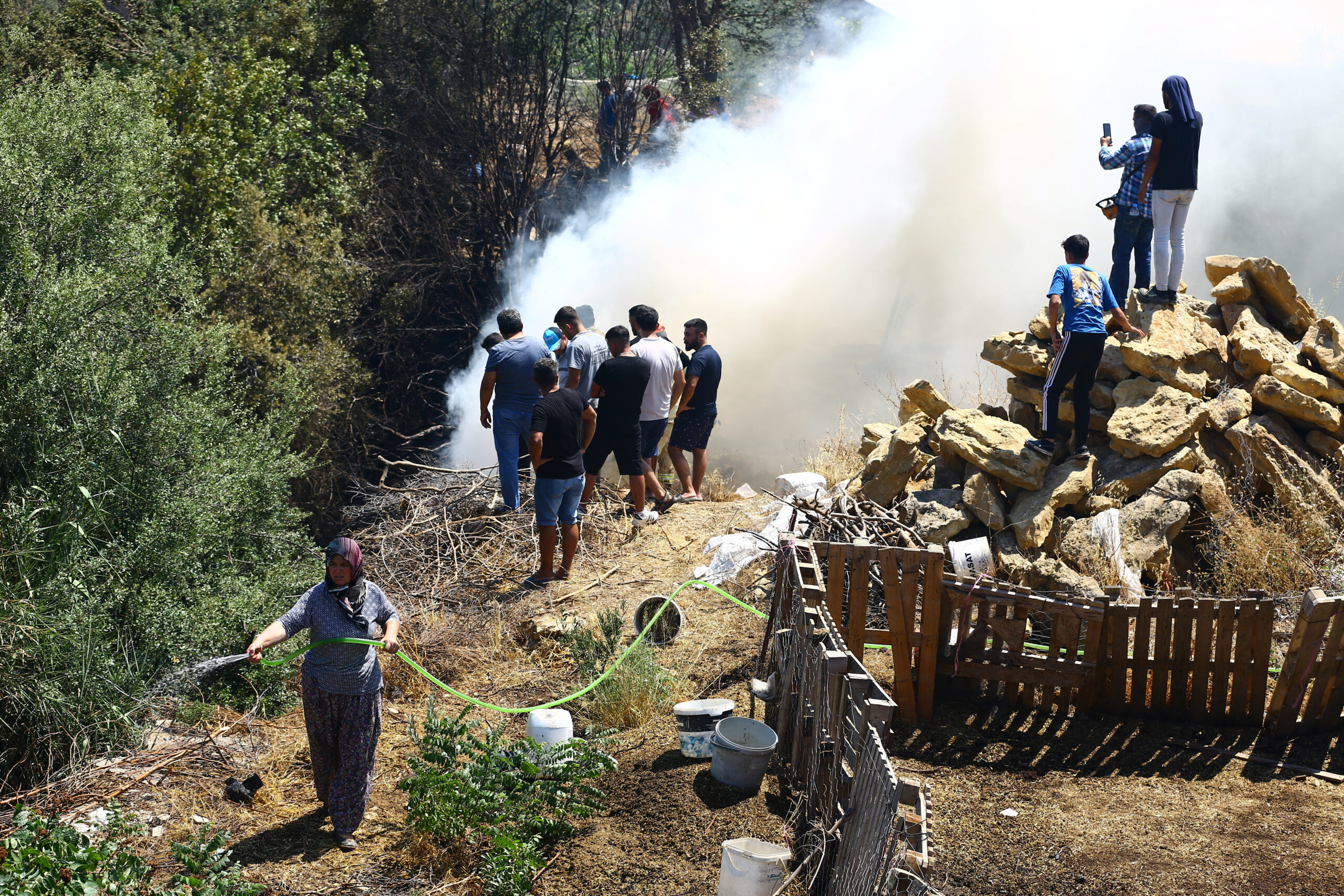 Άνθρωποι στέκονται δίπλα σε καπνούς που υψώνονται από την πυρκαγιά στην Αττάλεια / REUTERS / Kaan Soyturk