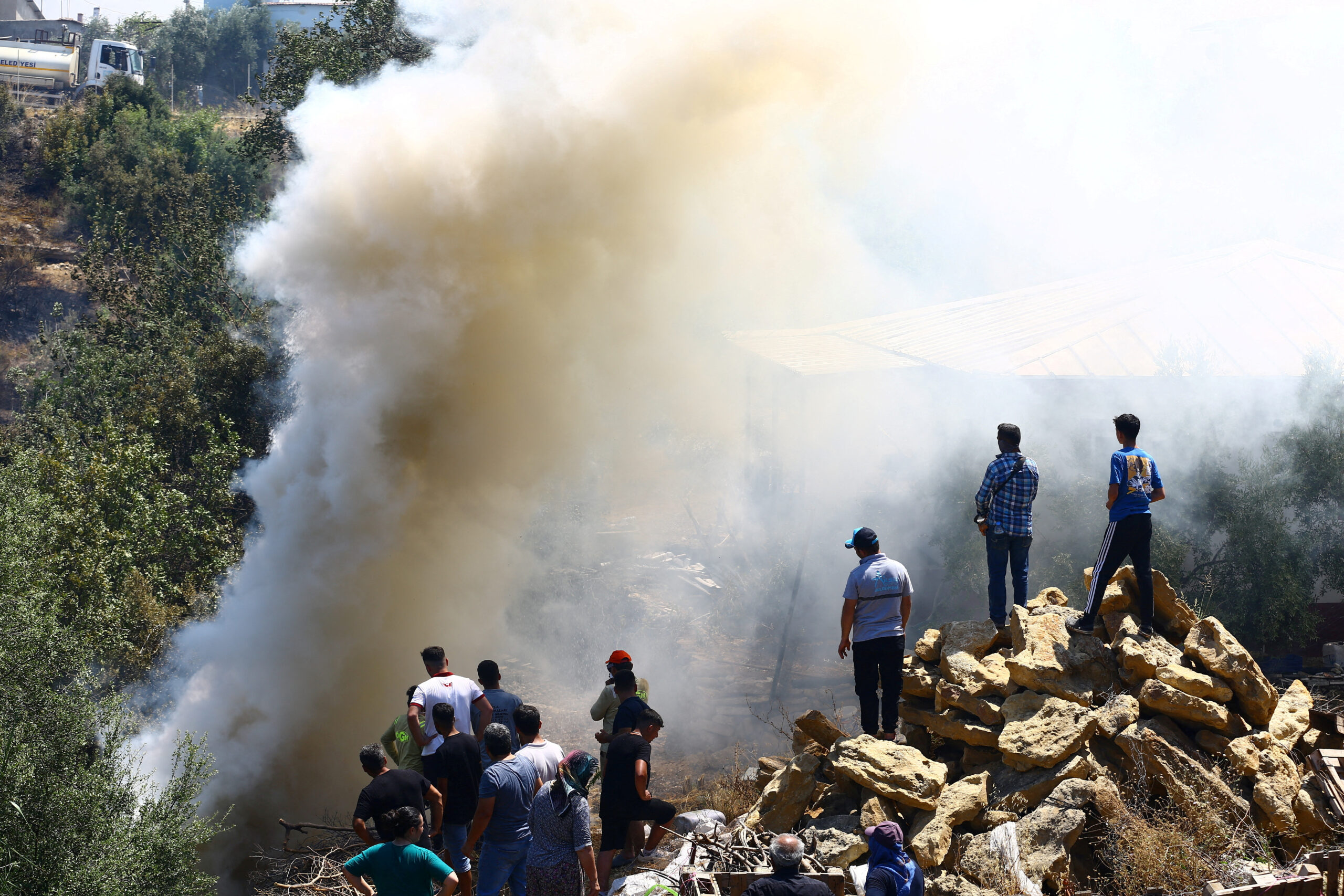 Άνθρωποι στέκονται δίπλα στον καπνό που υψώνεται από την πυρκαγιά στην Αττάλεια / REUTERS / Kaan Soyturk