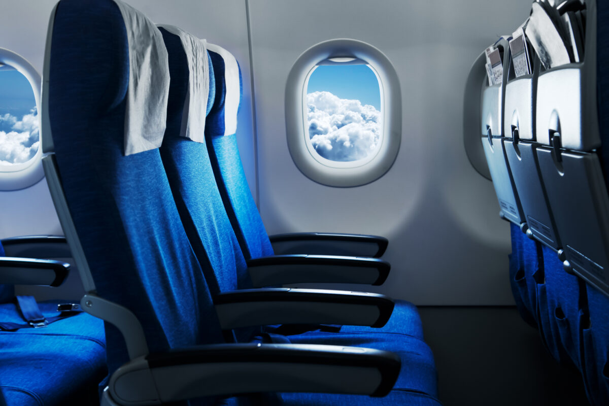 Empty air plane seats. Blue sky and clouds in the window. Airplane interior iStock