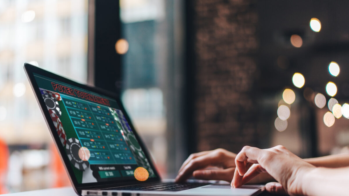 Close up cropped photo of girl hands using her laptop for taking part in online poker tournament.