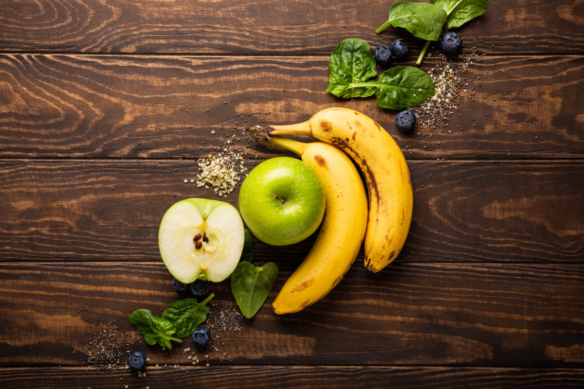 Ingredients fot healthy breakfast detox green smoothie bowl from banana, apples and spinach on wooden background. View from above.