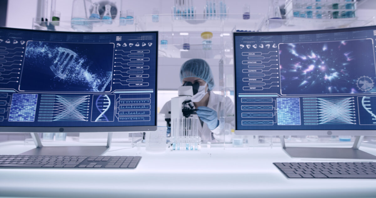 Scientist examines DNA models in modern Genetic Research Laboratory. Looking through laboratory glassware