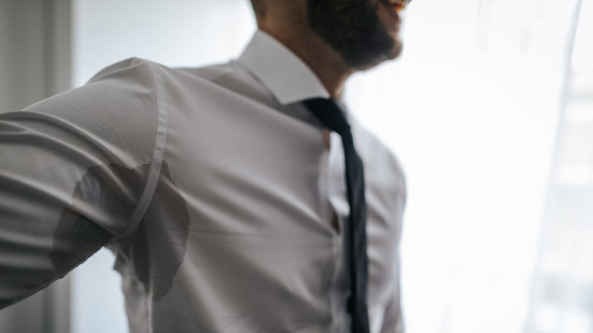 Man with hyperhidrosis sweating under armpit in shirt