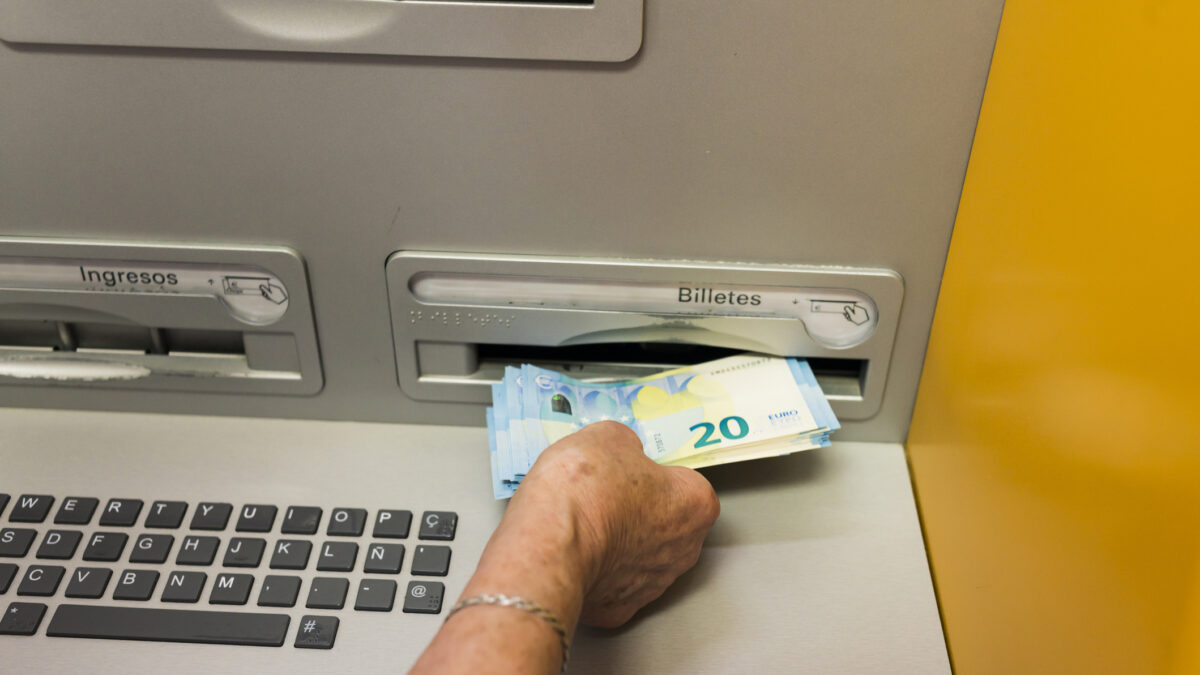 Arahal, Seville, Spain. May 25, 2022. Detail of an elderly woman's hand withdrawing cash from an ATM. Some elderly people have difficulty using ATMs.