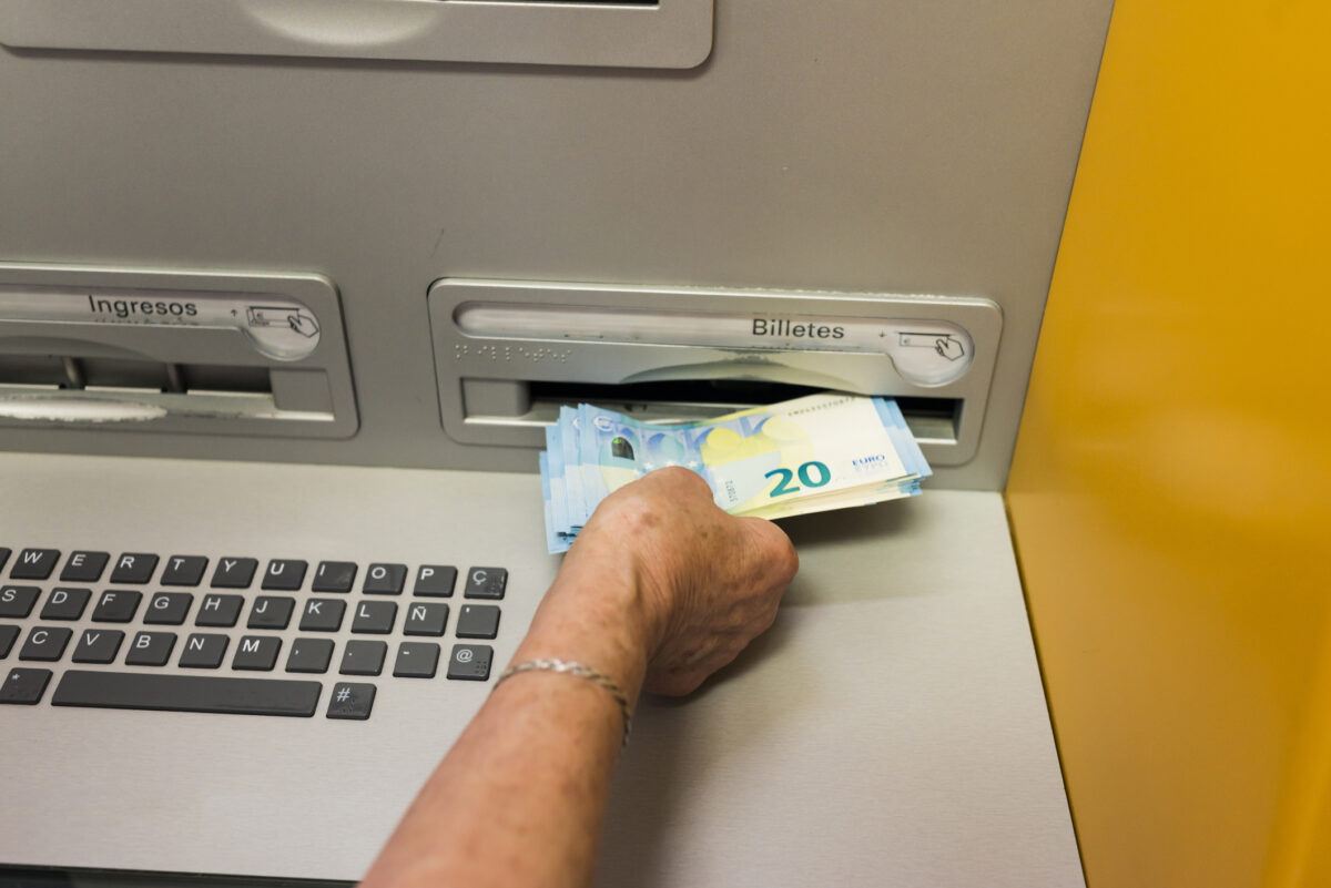 Arahal, Seville, Spain. May 25, 2022. Detail of an elderly woman's hand withdrawing cash from an ATM. Some elderly people have difficulty using ATMs.