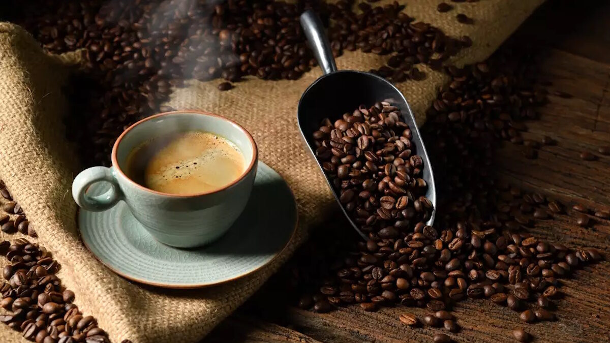 Cup of coffee with smoke and coffee beans on old wooden background