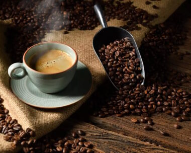 Cup of coffee with smoke and coffee beans on old wooden background