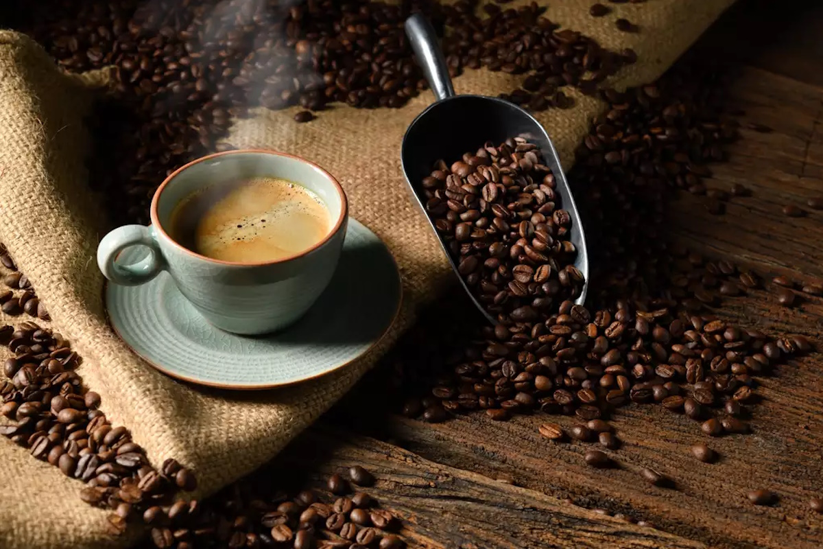 Cup of coffee with smoke and coffee beans on old wooden background