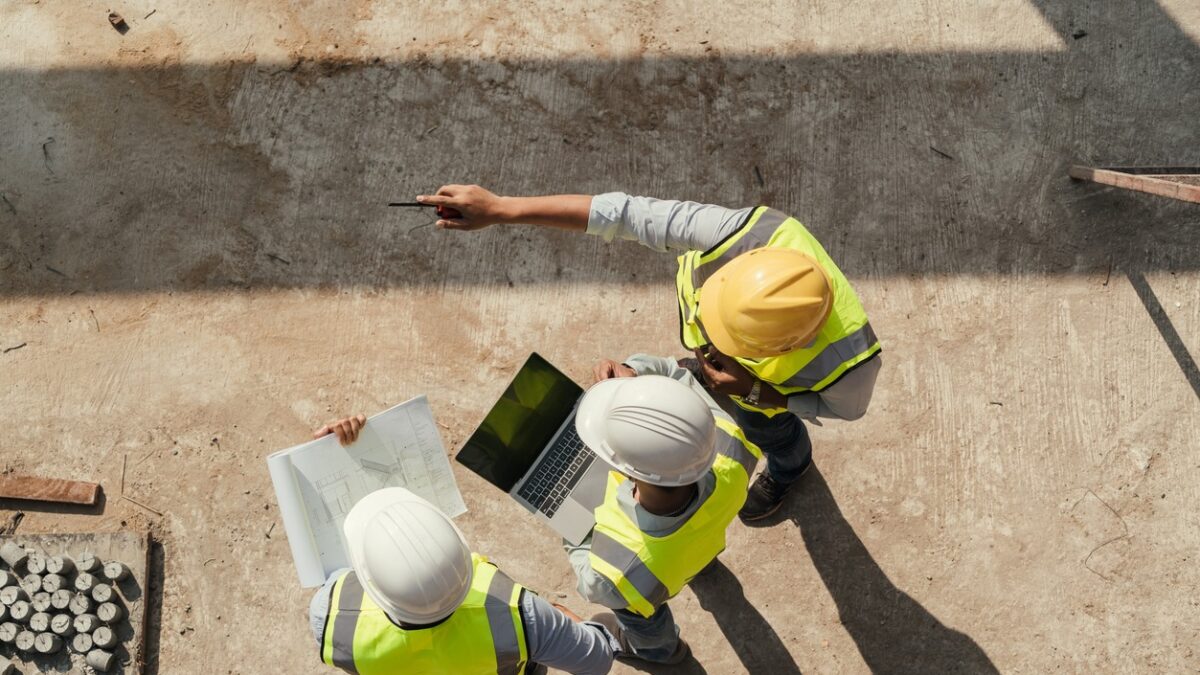Top view, Team engineer building inspection use tablet computer and blueprint working at construction site. Civil Engineer, Contractor and Architect discussing in construction site.