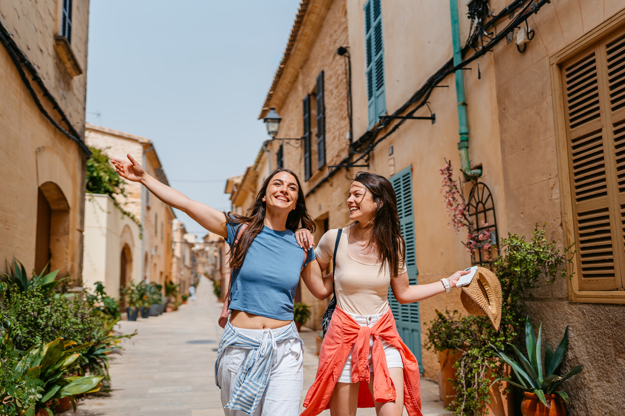 Two female friends having fun while walking on the street in Alcúdia in Mallorca in Spain.