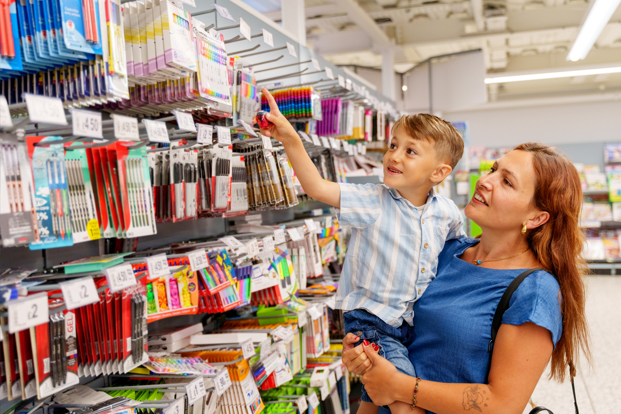 a child excitedly shopping for stationery on his mother's lap