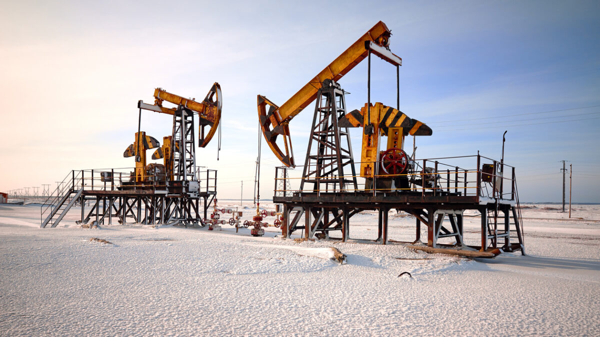Oil pump cold winter and snow. Back light, white cloudy and blue sky background, sunlight