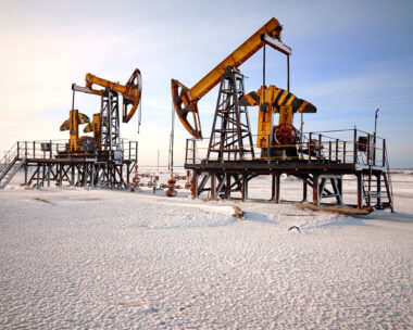 Oil pump cold winter and snow. Back light, white cloudy and blue sky background, sunlight