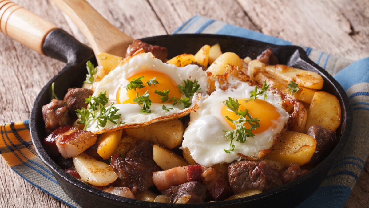 Tyrolean fried potatoes with meat, bacon and eggs in a pan close-up. horizontal