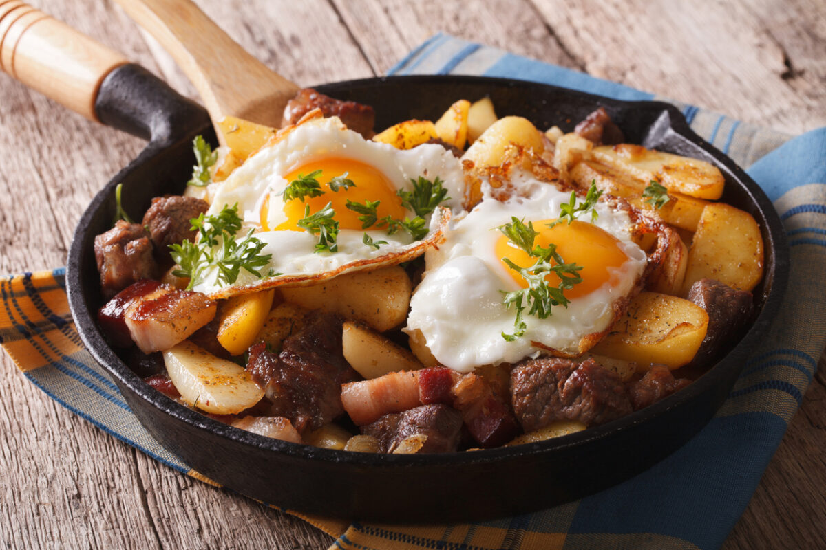 Tyrolean fried potatoes with meat, bacon and eggs in a pan close-up. horizontal