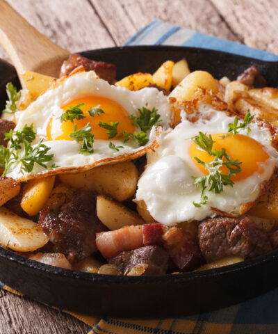 Tyrolean fried potatoes with meat, bacon and eggs in a pan close-up. horizontal