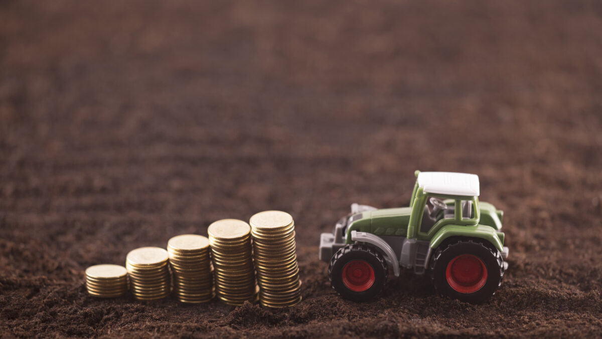 Tractor miniature with coins on fertile soil land