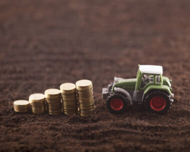 Tractor miniature with coins on fertile soil land