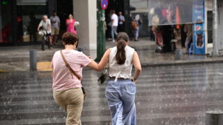 Δυο γυναίκες τρέχουν να προστατευτούν από τη βροχή