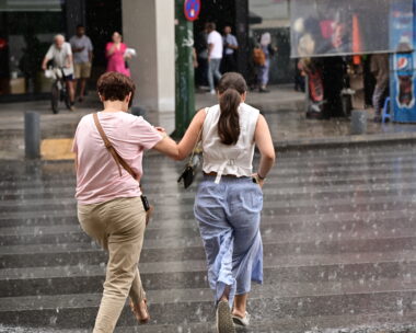 Δυο γυναίκες τρέχουν να προστατευτούν από τη βροχή