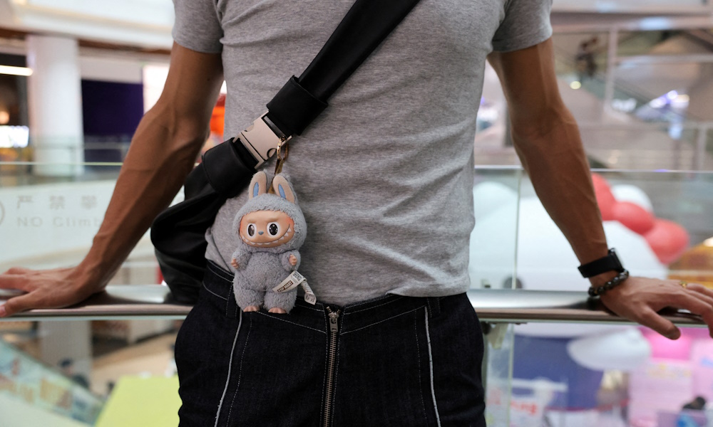 FILE PHOTO: A person carries a bag with a Labubu doll attached, outside Pop Mart's flagship store in Shanghai, China June 13, 2025. REUTERS