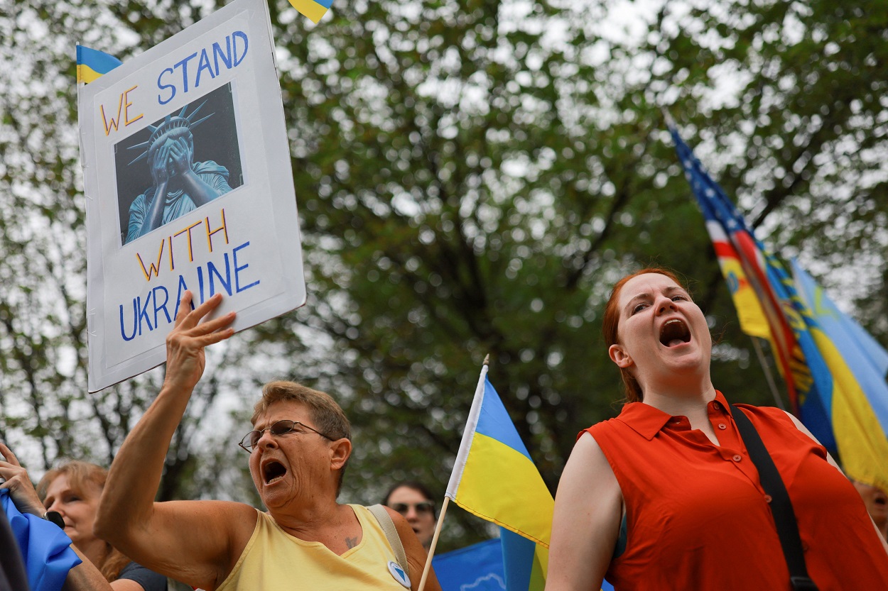 A woman holds a sign near the White House, ahead of expected meetings between U.S. President Donald Trump, Ukrainian President Volodymyr Zelenskiy, and European leaders, amid negotiations to end the Russian war in Ukraine, in Washington, D.C., U.S., August 18, 2025. REUTERS/Jose Luis Gonzalez
