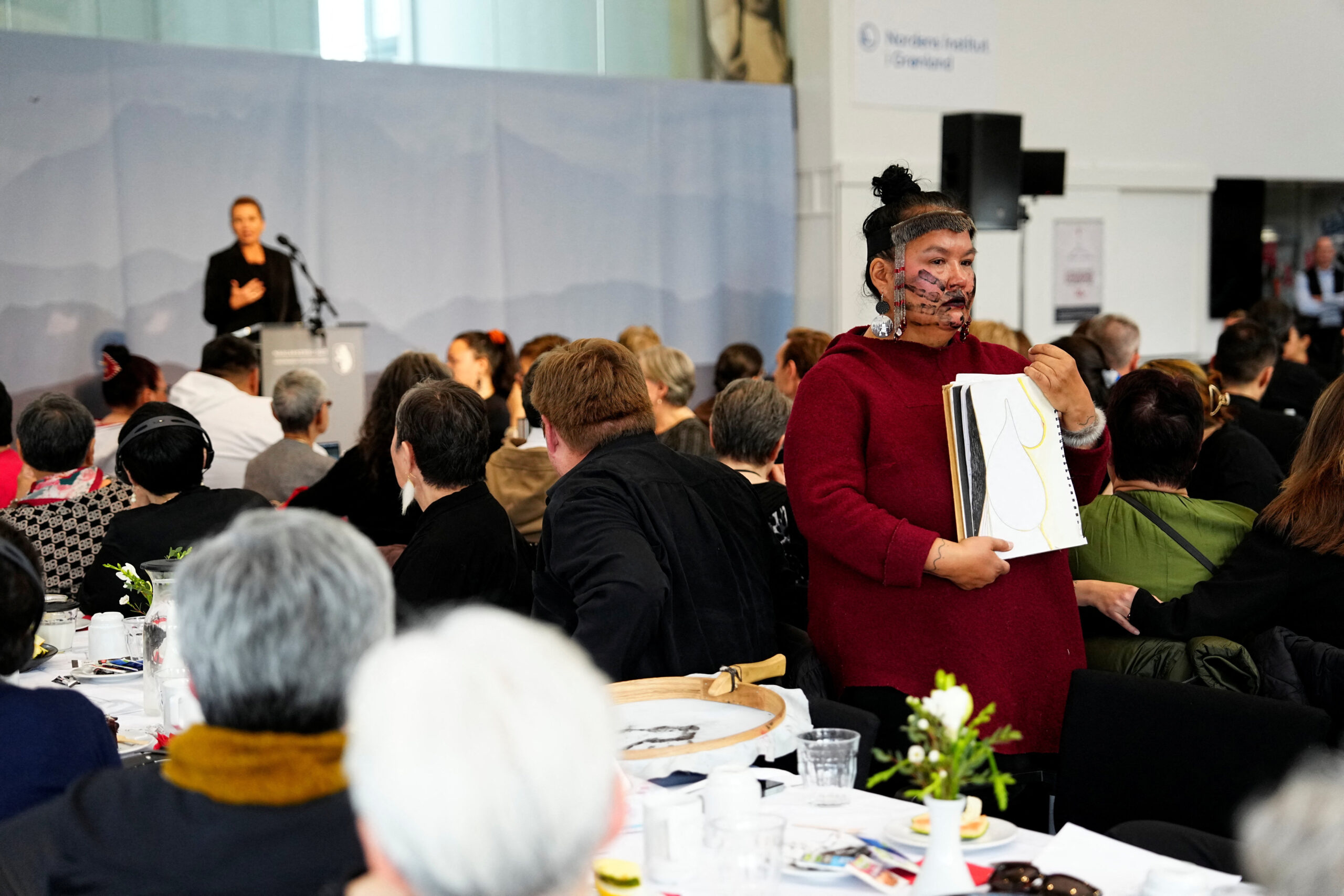 A woman of the Inhut race stands with her back facing the Prime Minister of Denmark, Court Fredericksen
