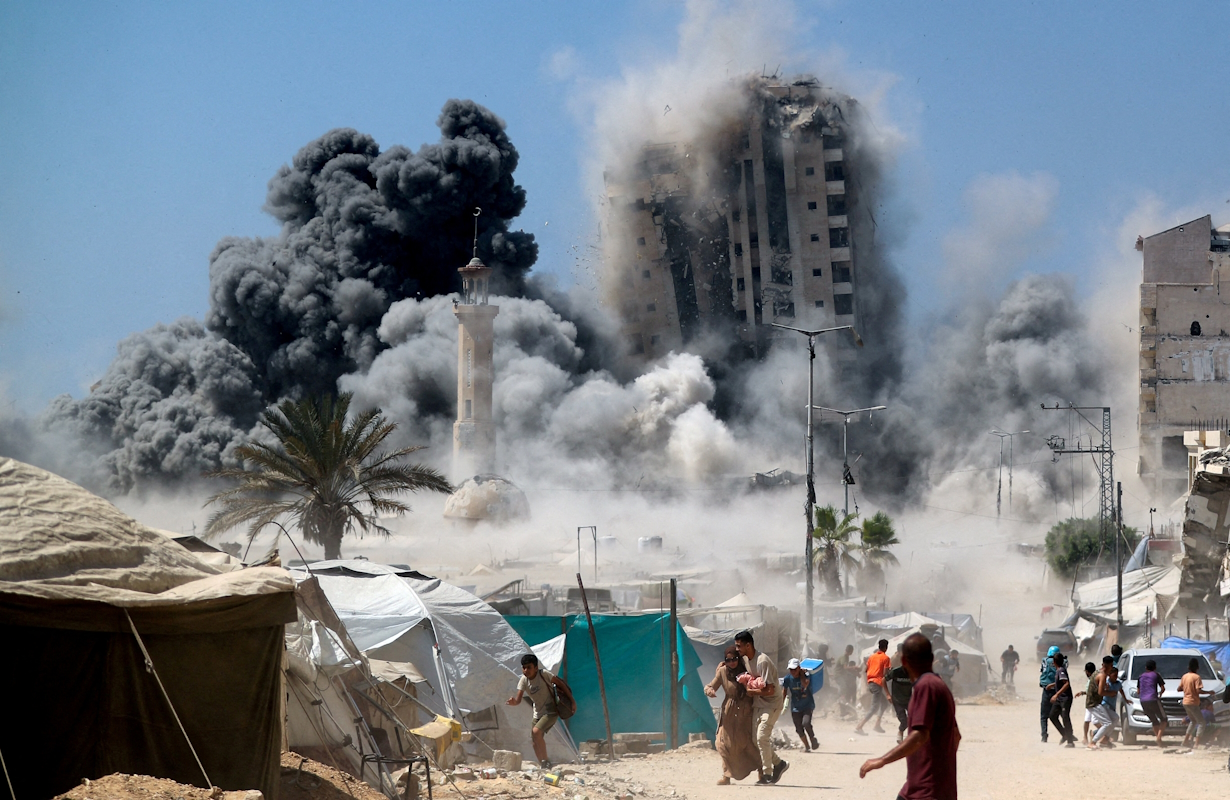 Palestinians run as the 15 -storey Mushtaha tower collapses after Israeli air raid on Gaza