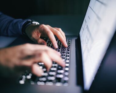 Close up of hands typing on laptop. Night work concept
