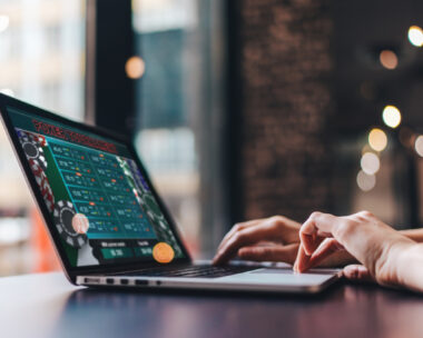 Close up cropped photo of girl hands using her laptop for taking part in online poker tournament.