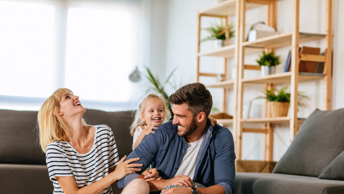 Cheerful family of three playing together at home