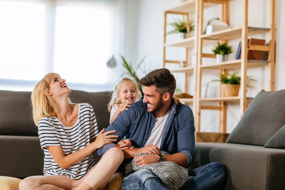 Cheerful family of three playing together at home