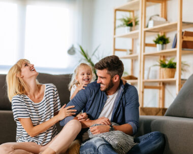 Cheerful family of three playing together at home