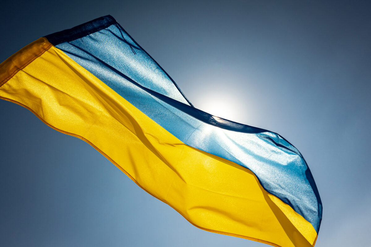 National flag of Ukraine waving outside on a wing facing the bright sky and the Sun
