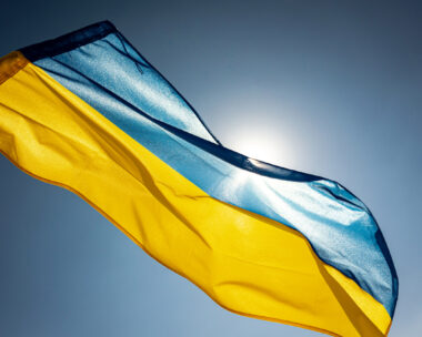 National flag of Ukraine waving outside on a wing facing the bright sky and the Sun