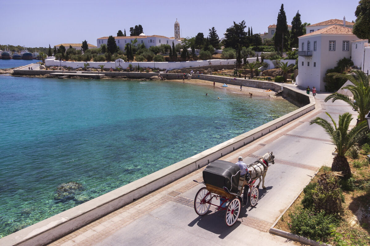 Spetses Island, Greece - May 14, 2017 : Horse drawn carriage on the way to the old harbor. Spetses, is a small picturesque island in the Saronic gulf, where the use of motorcars is not allowed.
